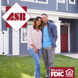 Couple smiling and standing together in front of a new home