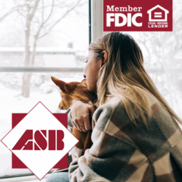 Woman snuggling her dog and looking outside at snowy yard