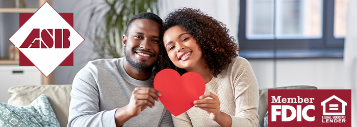 A young couple holding a red paper heart together