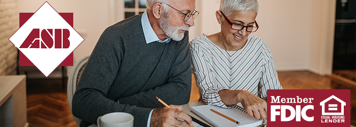 Older man and woman looking down at a notebook with pencils in hand