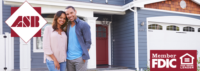 Couple smiling and standing together in front of a new home