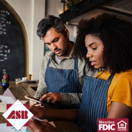 Man and woman looking at paperwork and wearing aprons in a business