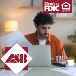 Young man holding files and using calculator in front of his laptop