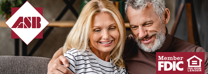 Older man and woman sitting together and smiling at a tablet