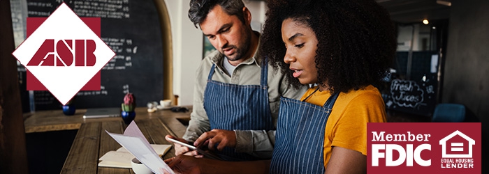 Man and woman looking at paperwork and wearing aprons in a business