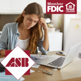 A young adult woman looking stressed at papers and laptop